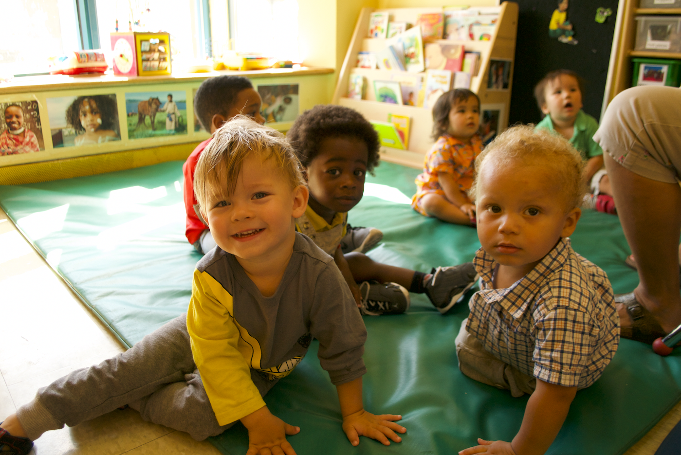 A group of toddlers sitting on a green mat