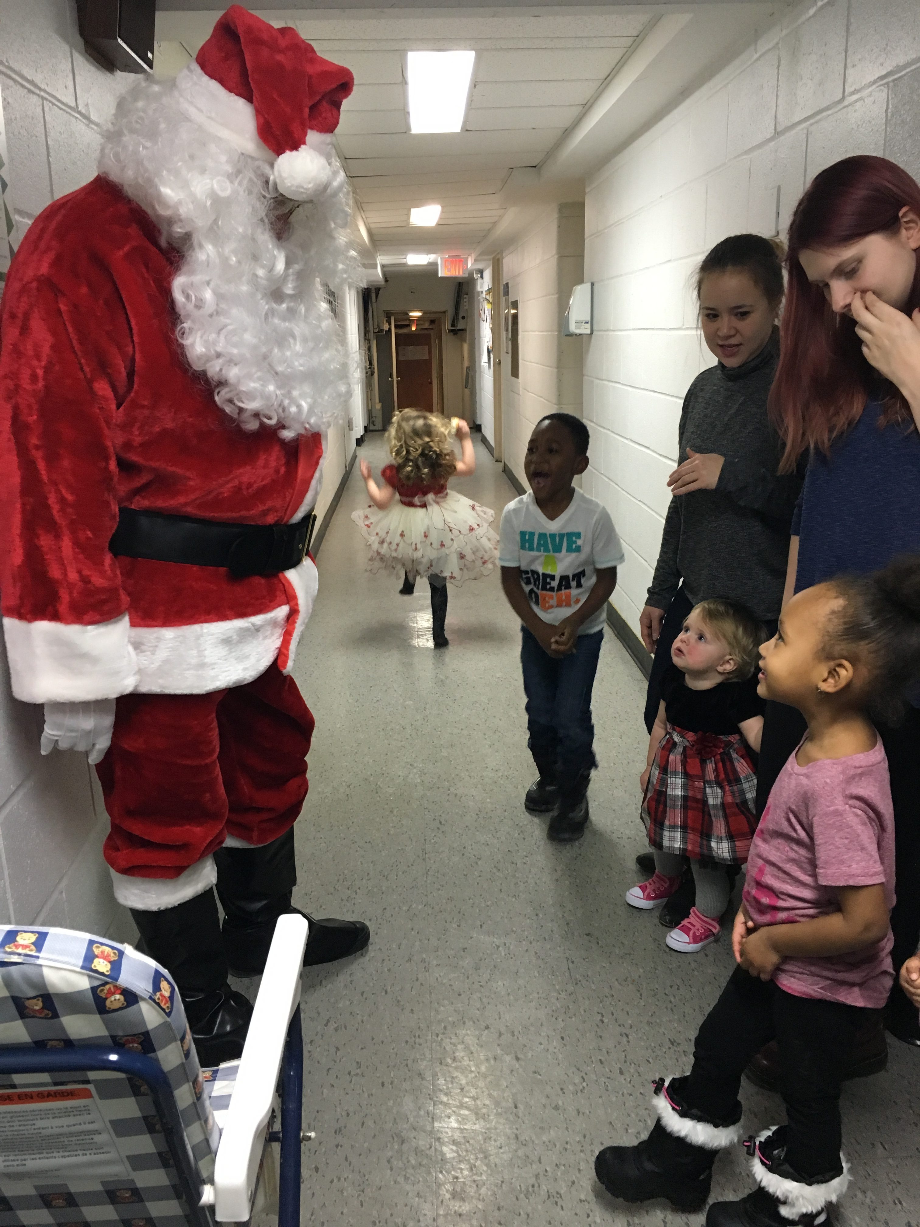 Santa meets with some young moms and children in the hall.